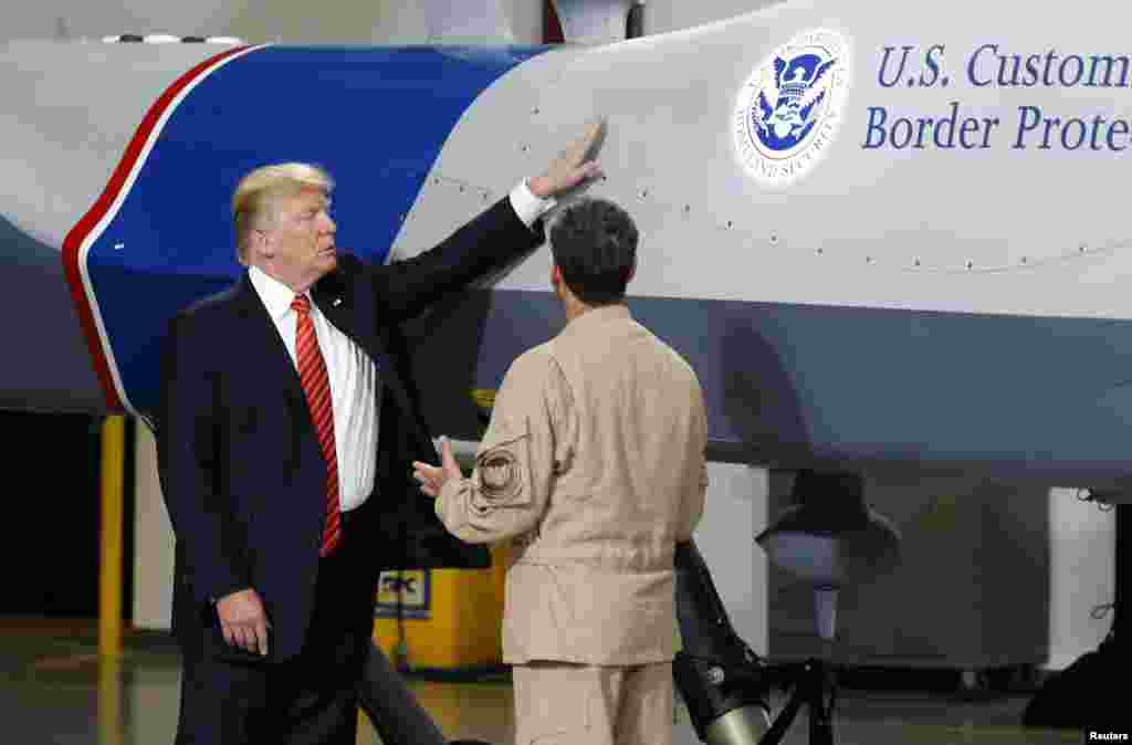 U.S. President Donald Trump puts his hand on a drone aircraft used to patrol the border at U.S. Customs and Border Patrol facility in Yuma, Arizona, Aug. 22, 2017. 