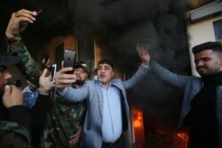 A commander of Iraq's Hashed al-Shaabi Jawad al-Talaibawi, center, takes a selfie at a gate of the U.S. embassy in Baghdad, Dec. 31, 2019, after supporters and members of the military network breached the outer wall of the compound.