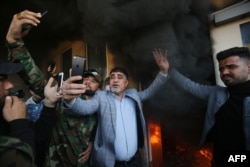 A commander of Iraq's Hashed al-Shaabi Jawad al-Talaibawi, center, takes a selfie at a gate of the U.S. embassy in Baghdad, Dec. 31, 2019, after supporters and members of the military network breached the outer wall of the compound.