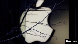 FILE - An Apple company logo is seen behind tree branches outside an Apple store in Beijing, Dec. 14, 2018. 