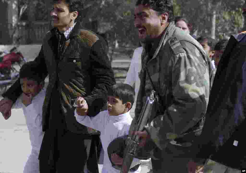 A police officer shouts as children are rescued following a suicide attack on a church in Quetta, Pakistan, Sunday, Dec. 17, 2017.