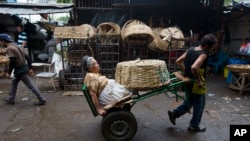 FILE - Vendor Carmen Diaz, 84, is pulled by a market porter as she makes her way home at the end of her work day in the Oriental Market in Managua, Nicaragua, April 30, 2015.