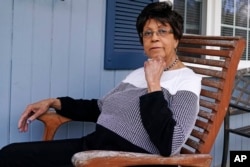 Roberta Wolff, a descendant of Tony, Cuba and Darby Vassall who were enslaved by Harvard benefactors in the institution's first decades, poses on the front porch of her family home, Wednesday, April 27, 2022, in Bellingham, Mass. (AP Photo/Charles Krupa)