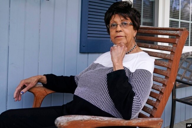 Roberta Wolff, a descendant of Tony, Cuba and Darby Vassall who were enslaved by Harvard benefactors in the institution's first decades, poses on the front porch of her family home, Wednesday, April 27, 2022, in Bellingham, Mass. (AP Photo/Charles Krupa)