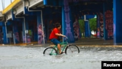 Un hombre atraviesa en bicicleta una calle inundada por el huracán Beryl en Playa del Carmen, México, el 5 de julio de 2024.