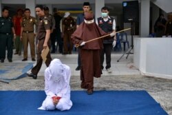 Perempuan pertama yang menjadi algojo hukum cambuk bersiap mencambuk seorang perempuan di Banda Aceh, 10 Desember 2019. (Foto: AFP)