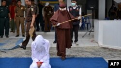 Perempuan pertama yang menjadi algojo hukum cambuk bersiap mencambuk seorang perempuan di Banda Aceh, 10 Desember 2019. (Foto: AFP)