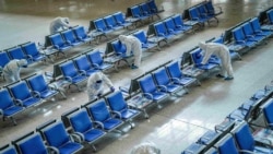 身穿防护服的工人在武汉火车站给座椅消毒，为武汉开城做准备。（2020年3月25日）