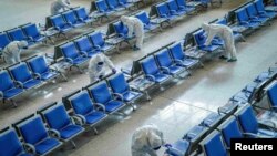 身穿防护服的工人在武汉火车站给座椅消毒，为武汉开城做准备。（2020年3月25日）