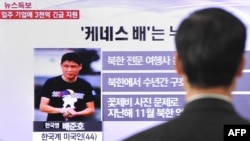 A passerby watches a local television broadcast in Seoul on May 2, 2013 showing a report and picture of Kenneth Bae (L), a Korean-American tour operator detained in North Korea. 
