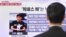 A passerby watches a local television broadcast in Seoul on May 2, 2013 showing a report and picture of Kenneth Bae (L), a Korean-American tour operator detained in North Korea. 