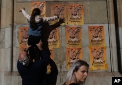 A girl pastes a banner on a wall that reads in Catalan: "Freedom for the Political Prisoners", during a protest against the decision of a judge to jail ex-members of the Catalan government at the University square in Barcelona, Spain,Nov. 5, 2017.