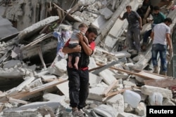 A man carries an injured child after airstrikes on the rebel-held al-Qaterji neighborhood of Aleppo, Syria Sept. 21, 2016.