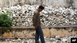 A Cambodian man walks past one of the many killing fields sites at a school on the outskirts of Phnom Penh.