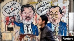 A protester walks past a graffiti during a march at Tahrir Square in Cairo, February 11, 2013. The march, was organized by Egyptians who oppose Egypt's President Mohamed Morsi and members of the ruling Muslim Brotherhood on the second anniversary of the r