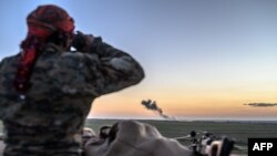 A Syrian Democratic Forces (SDF) fighter uses binoculars to inspect the embattled village of Baghuz, Syria, Feb. 19, 2019. 