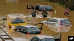 Helpers check for victims in flooded cars on a road in Erftstadt, Germany, July 17, 2021. 