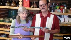 Donor Steven Martin and University of Idaho curator Priscilla Wegars hold antique opium pipes. (VOA/T. Banse) 