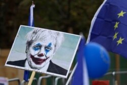 Brexit opponents hold a placard showing Prime Minister Boris Johnson portrayed as the Joker as they take part in a "People's Vote" protest march calling for another referendum on Britain's EU membership, in London, Oct. 19, 2019.