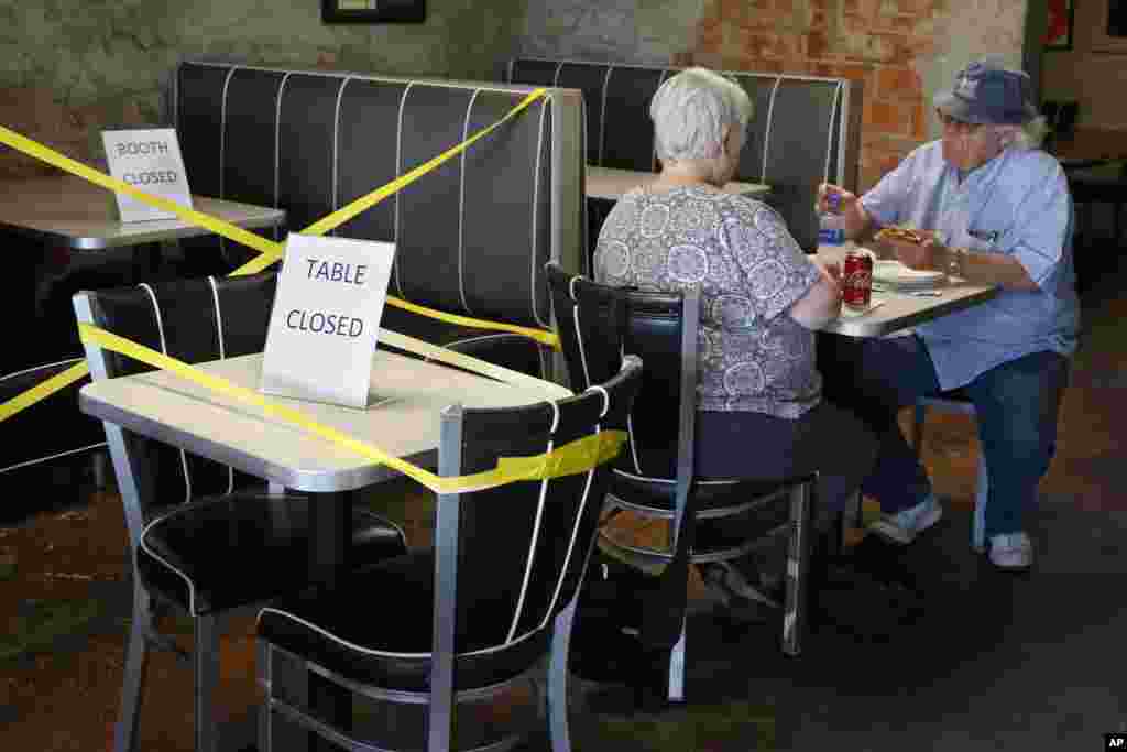 George Kolokotronex, right, and his wife, Nancy Kolokotronex, left, eat lunch at Falcone&#39;s Pizzeria Friday, May 1, 2020, in Oklahoma City, as restaurants are allowed to open for in person dining. Tables are taped off to promote social distancing. (AP Phot