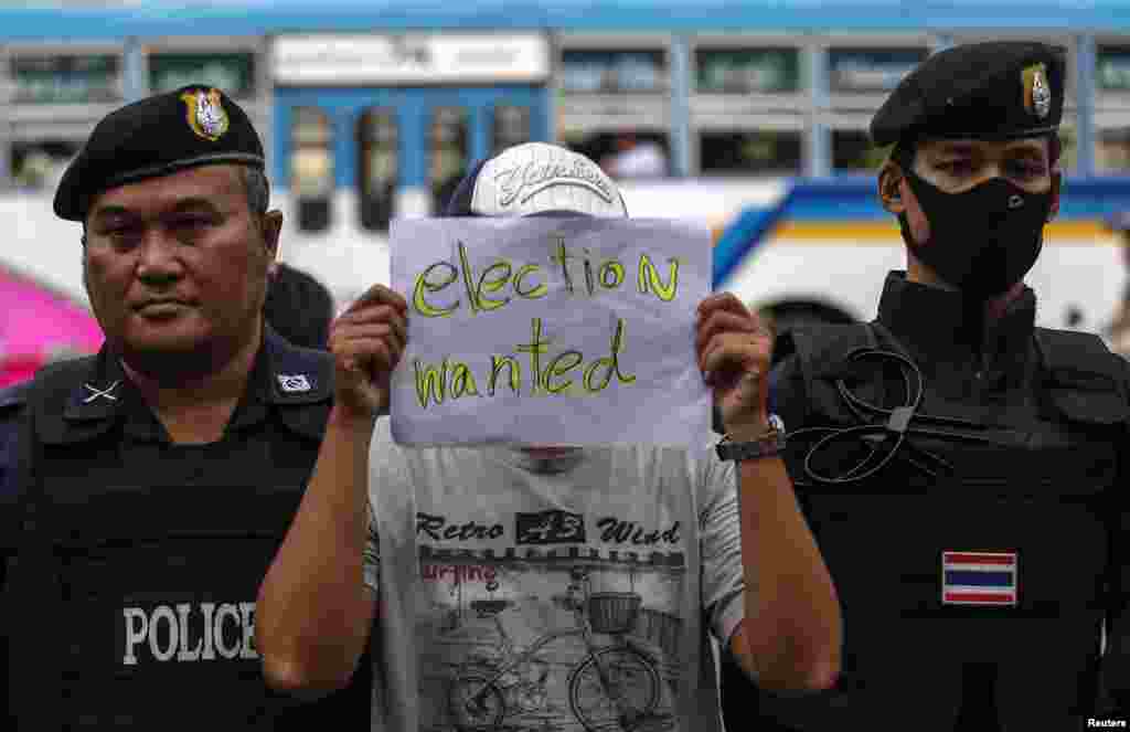 Seorang demonstran memegang kertas bertuliskan desakan atas penyelenggaraan pemilu dalam protes melawan kependudukan militer di Monumen Kemenangan di Bangkok (27/5). (Reuters/Athit Perawongmetha)