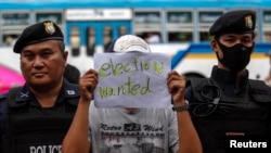 Seorang demonstran memegang kertas bertuliskan pesan saat bergabung dengan demonstran lainnya yang berunjuk rasa menentang aturan militia di monument Kemenangan (Victory Monument) di Bangkok (27/5).