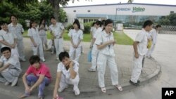 Chinese workers stand outside the Ichikoh Valeo factory, a Japanese-owned plant that makes head lamps and fog lights for the auto industry, in Foshan, southern China's Guangdong province, 18 Jun 2010