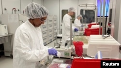 FILE - An Aastrom Biosciences production assistant works at 'priming' cell cassettes for incubation in the clean room laboratory at their headquarters in Ann Arbor, Michigan.