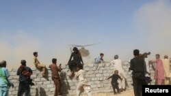 Residents gather as a rescue helicopter with medical supplies lands following an earthquake in Harnai, Balochistan, Pakistan.