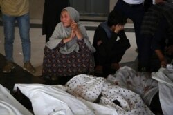 FILE - Family members and relatives mourn inside a hospital while sitting next to the bodies of victims who died in a blast outside a school in the west Kabul district of Dasht-e-Barchi, May 8, 2021.