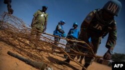 Un soldat de la paix de la MINUAD marquant avec des branches l'emplacement d'un projectile de mortier récemment abandonné dans le camp d'Alabassi pour personnes déplacées à l'intérieur du pays (PDI), à Mellit, Darfour Nord, le 25 mars 2014.