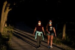 People wearing face masks to combat the spread of coronavirus walk in a public park in Madrid, Spain, May 6, 2020.