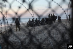 FILE - U.S. Border Patrol agents are seen though the border structure from the Mexican side at a beach in the Pacific Ocean in Tijuana, Mexico, Nov. 16, 2018.