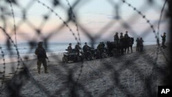 FILE - U.S. Border Patrol agents are seen though the border structure from the Mexican side at a beach in the Pacific Ocean in Tijuana, Mexico, Nov. 16, 2018.