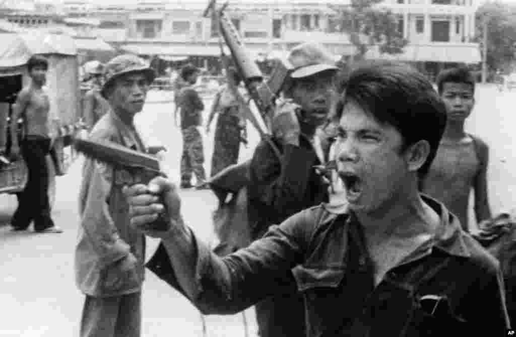 A Khmer Rouge soldier waves his pistol and orders store owners to abandon their shops in Phnom Penh, Cambodia, on April 17, 1975 as the capital fell to the communist forces. A large portion of the city&#39;s population was reportedly forced to evacuate. Photo from West German television film. (AP Photo/Christoph Froehder)&nbsp;