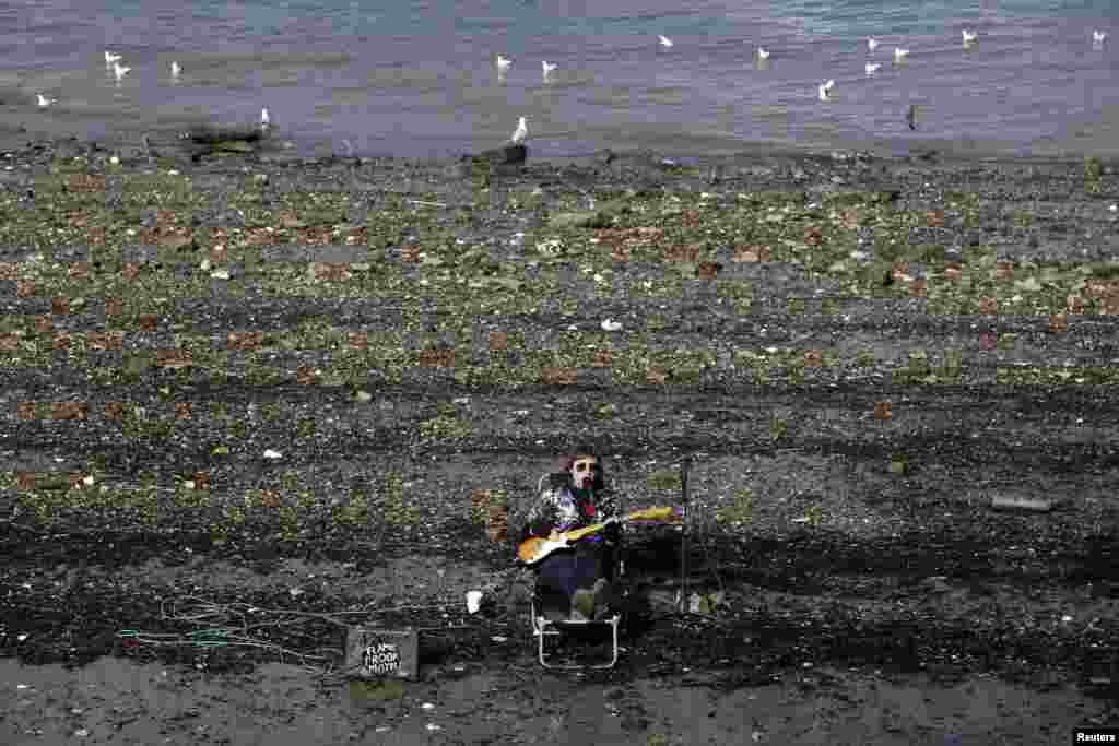 一位街頭藝人坐在倫敦中部的泰晤士河南岸彈著電吉他。