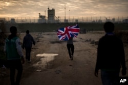 A man runs with a British flag inside a makeshift camp known as "the jungle" near Calais, northern France, Oct. 25, 2016.
