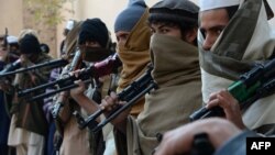 Afghan former Taliban fighters are photographed holding weapons before they hand them over as part of a government peace and reconciliation process at a ceremony in Jalalabad, Feb. 8, 2015. 