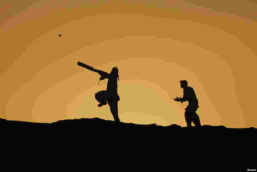 Boys are silhouetted against the setting sun while playing cricket in Karachi, Pakistan.