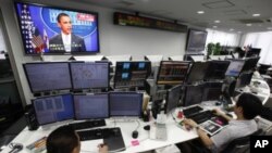 Employees of a foreign exchange firm monitor screens, with a television news reports that President Barack Obama announced US debt limit deal, in Tokyo, August 1, 2011
