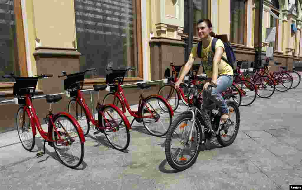 Một phụ nữ đi xe đạp vượt qua địa điểm cho thuê xe đạp tại trung tâm Moscow. Hy vọng làm giảm áp lực lưu thông tại một trong những thành phố kẹt xe nhất thế giới, Moscow sẽ phát động rộng rãi phong trào đi xe đạp thuê vào ngày thứ Bảy dù có những lo ngại về an toàn trên đường phố.