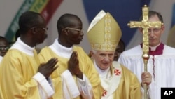 Pope Benedict XVI, second right, is accompanied by members of the clergy as he leaves following Sunday Mass, at the national stadium in Cotonou, Benin, November 20, 2011.
