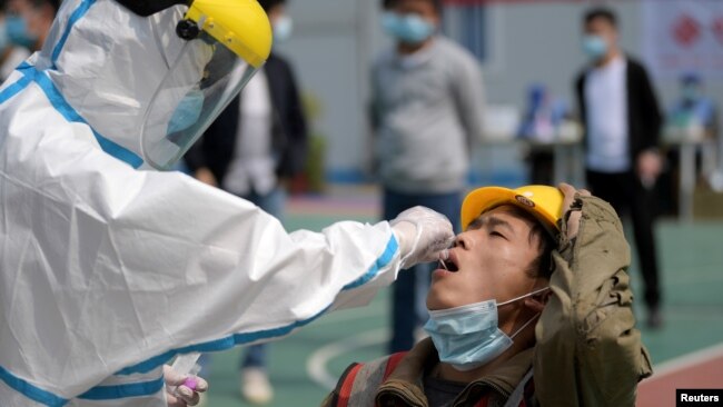武汉一位医护人员正在对一名建筑工人采取进行核酸检测的样本。