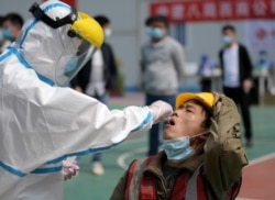 FILE PHOTO: A worker in a protective suit collects a swab from a construction worker for nucleic acid test in Wuhan, Hubei province, the epicentre of the novel coronavirus disease (COVID-19) outbreak in China, April 7, 2020.