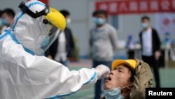 武汉一位医护人员正在对一名建筑工人采取进行核酸检测的样本。