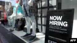 FILE - A now hiring sign is posted in the window of a clothing store in San Francisco, California. 