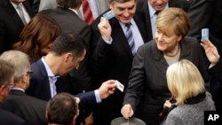 ນາຍົກລັດຖະມົນຕີ ທ່ານນາງ Angela Merkel (ຂວາ) ປ່ອນບັດລົງຄະແນນ ທີ່ ສະພາເຢຍຣະມັນ ໃນນະຄອນ Berlin ທີ 4 ທັນວາ 2015. 
