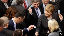 German Chancellor Angela Merkel, right, casts her vote at the German Federal Parliament in Berlin, Germany, Dec.4, 2015. 