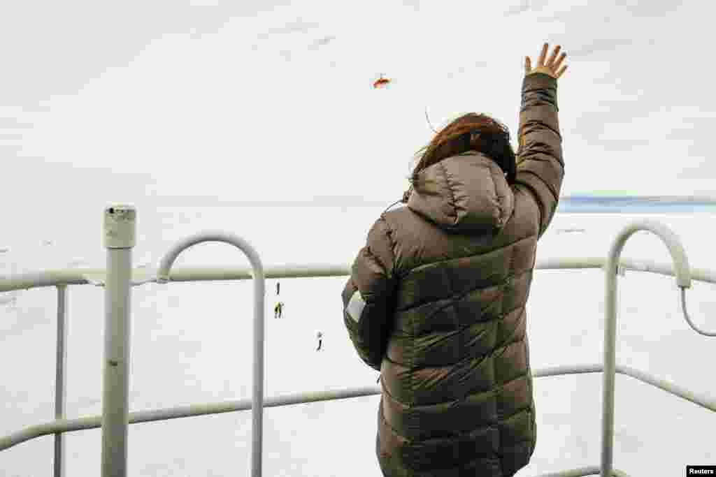 Nicole De Losa, a passenger on board the MV Akademik Shokalskiy, waves to a helicopter sent from the Chinese icebreaker Xue Long (Snow Dragon) to assess ice conditions, Antarctica, Dec. 29, 2013.