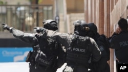 FILE - Armed police officers point as they stand at the ready close to a cafe under siege at Martin Place in Sydney, Australia, Dec. 15, 2014. 